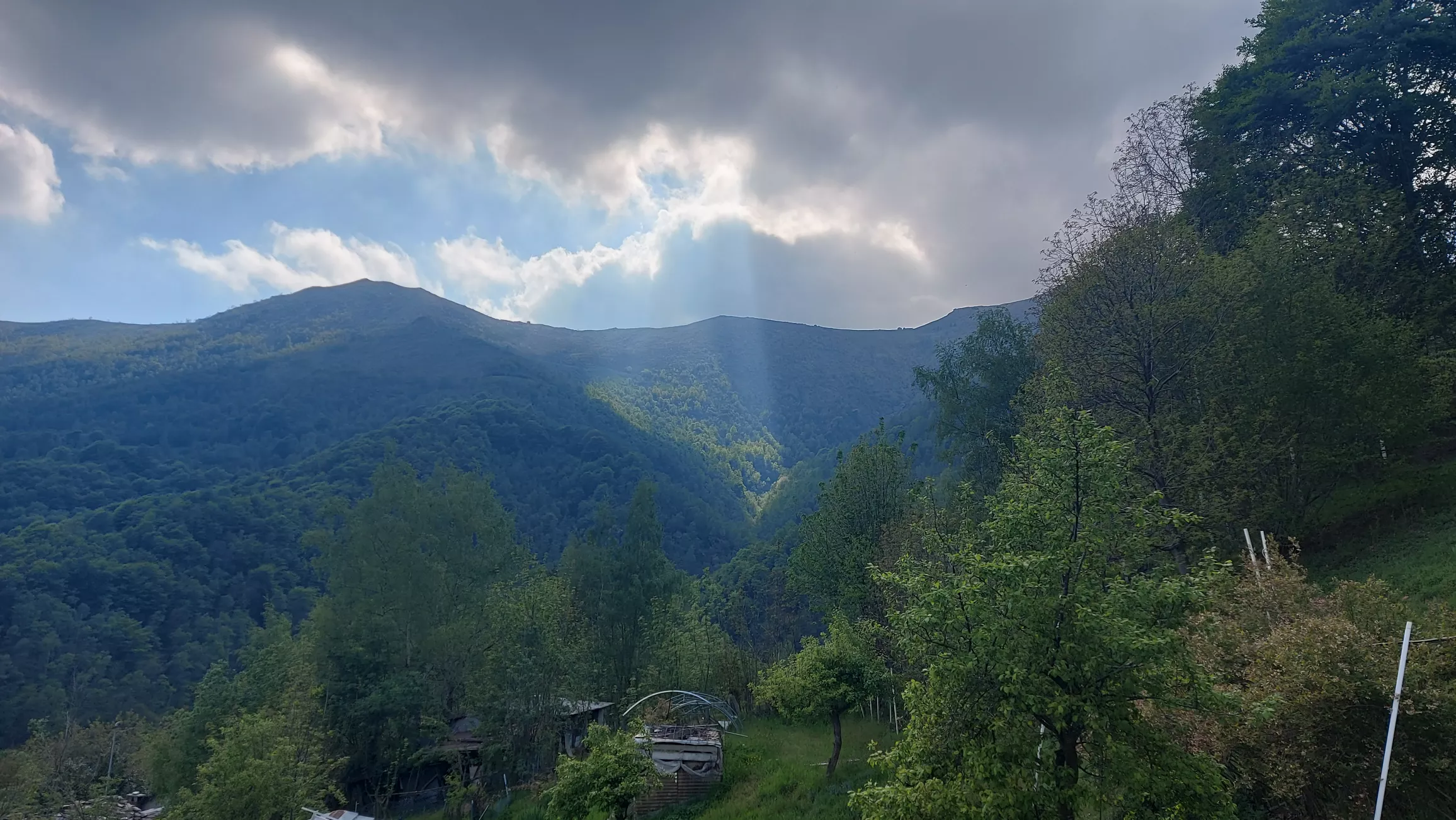Sonnenstrahlen durchbrechen eine dichte Wolkendecke über einer weiten Landschaft – Sinnbild für Frequenz und bewusstes Leben